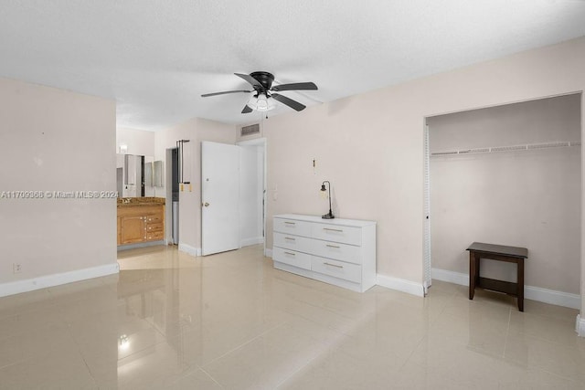 tiled bedroom featuring ceiling fan, ensuite bathroom, and a closet