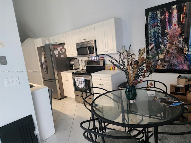 kitchen with light tile patterned floors, stainless steel appliances, and white cabinetry