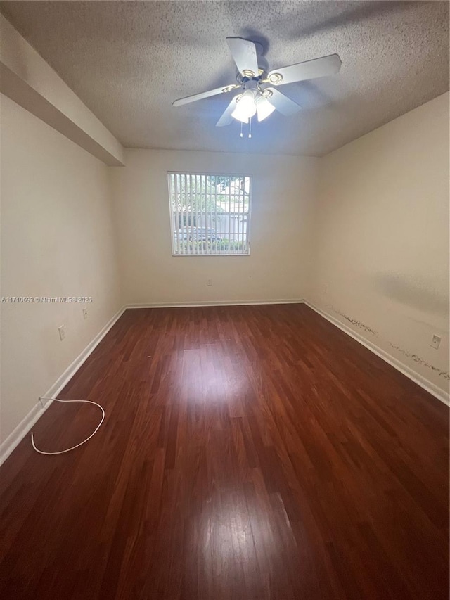 empty room featuring a textured ceiling, ceiling fan, and dark wood-type flooring