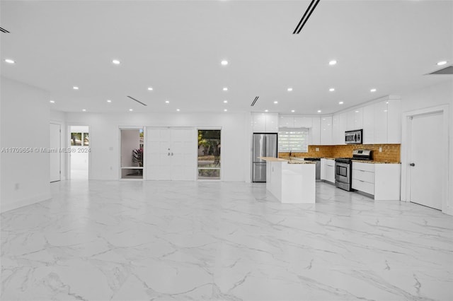 kitchen with appliances with stainless steel finishes, tasteful backsplash, sink, a center island, and white cabinetry