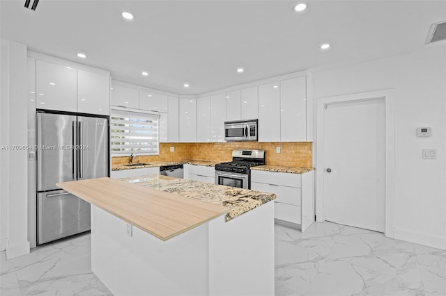 kitchen featuring white cabinets, appliances with stainless steel finishes, decorative backsplash, and sink