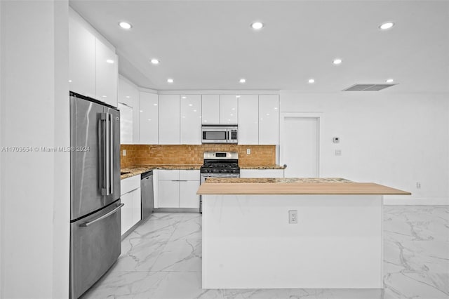 kitchen featuring appliances with stainless steel finishes, a center island, tasteful backsplash, and white cabinetry