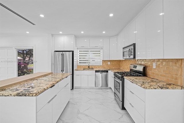 kitchen featuring appliances with stainless steel finishes, tasteful backsplash, white cabinetry, and sink