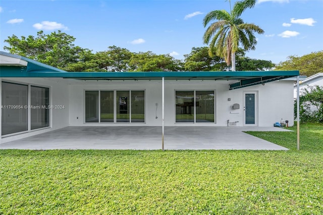 rear view of house with a lawn and a patio