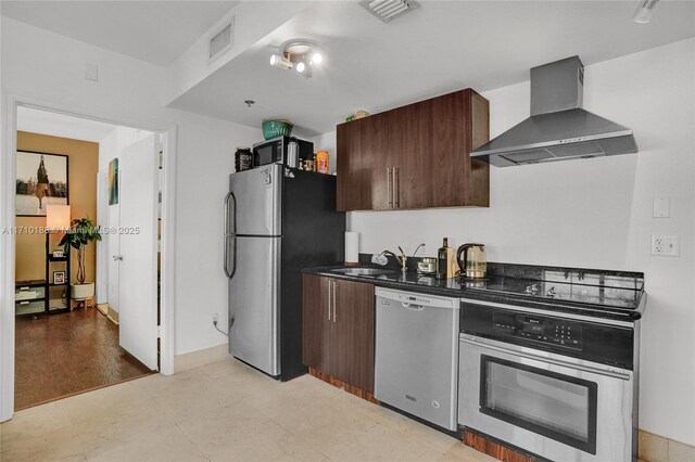 kitchen with dark brown cabinets, wall chimney range hood, sink, and stainless steel appliances