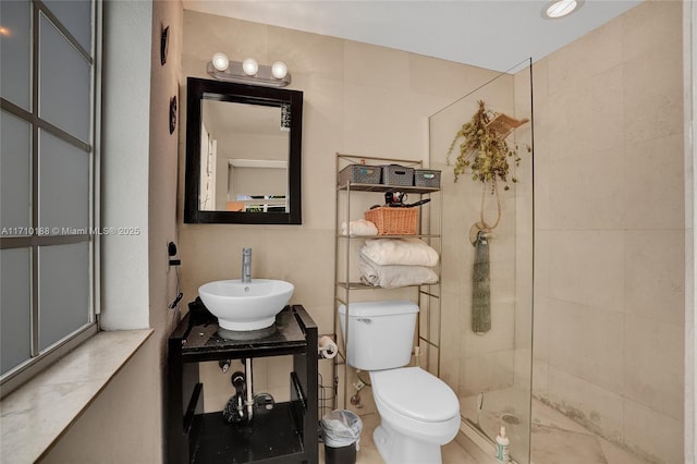 bathroom with sink, toilet, and a tile shower