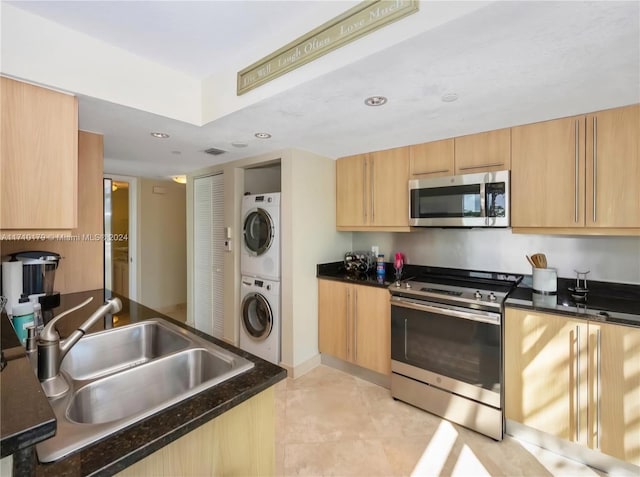 kitchen featuring appliances with stainless steel finishes, light brown cabinetry, stacked washer / drying machine, and sink