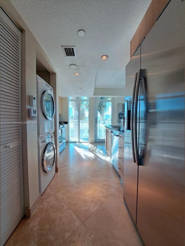 corridor featuring a textured ceiling, french doors, and stacked washer and clothes dryer