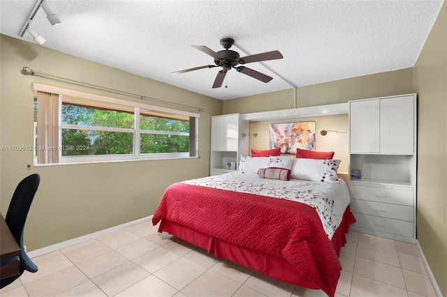 bedroom featuring ceiling fan, light tile patterned flooring, a textured ceiling, and track lighting