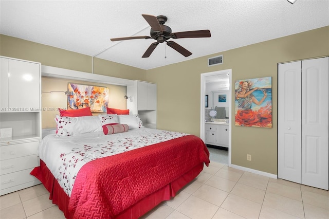 tiled bedroom featuring a textured ceiling, ensuite bath, and ceiling fan