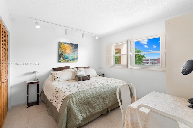 bedroom featuring a closet, rail lighting, and a textured ceiling