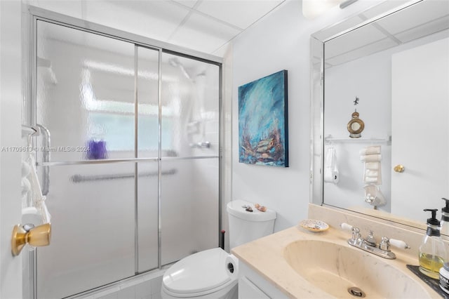 bathroom with a paneled ceiling, vanity, toilet, and walk in shower