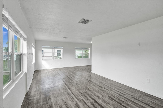 spare room featuring a textured ceiling and dark hardwood / wood-style floors