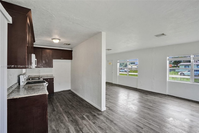 kitchen with dark brown cabinets, dark wood-type flooring, and a textured ceiling