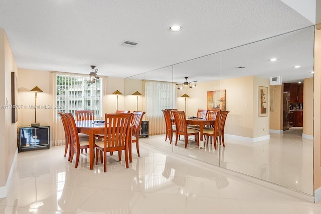 tiled dining area with ceiling fan and a textured ceiling