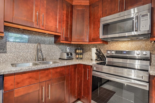 kitchen with sink, stainless steel appliances, tasteful backsplash, light stone counters, and tile patterned flooring