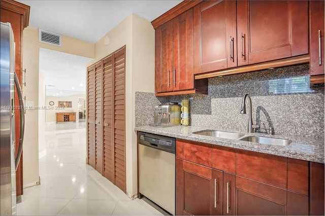 kitchen with light stone countertops, sink, tasteful backsplash, light tile patterned floors, and appliances with stainless steel finishes