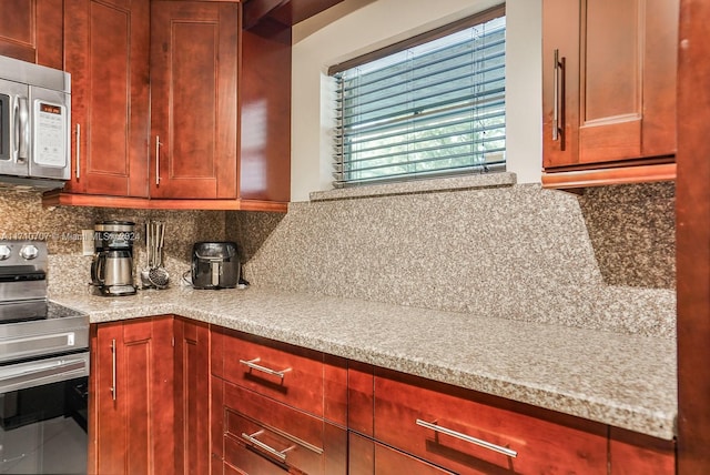 kitchen featuring light stone counters, backsplash, and appliances with stainless steel finishes