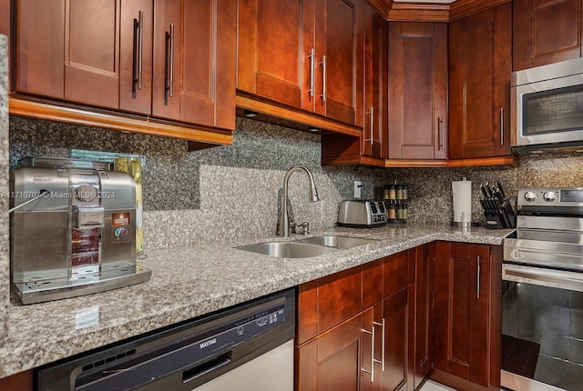 kitchen featuring backsplash, stainless steel appliances, light stone counters, and sink