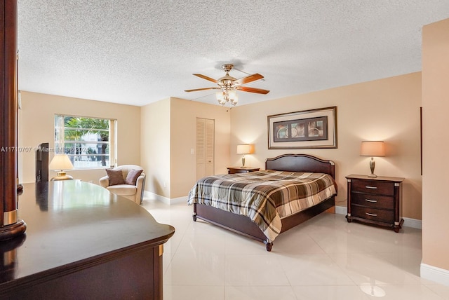 bedroom featuring ceiling fan, a closet, light tile patterned floors, and a textured ceiling