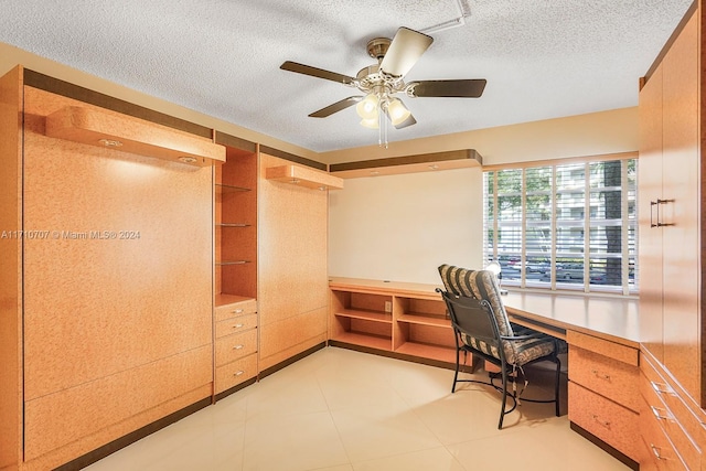 office with a textured ceiling, ceiling fan, and built in desk