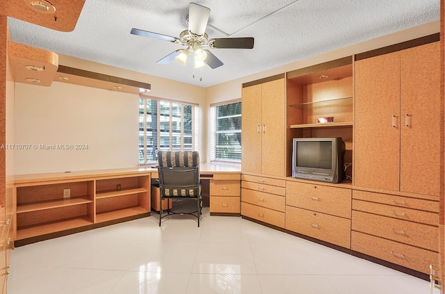 tiled office space with built in shelves, ceiling fan, and a textured ceiling