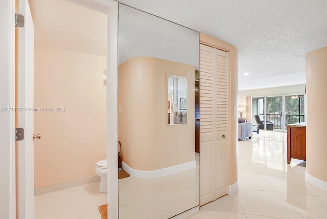 hallway with light tile patterned floors and a textured ceiling