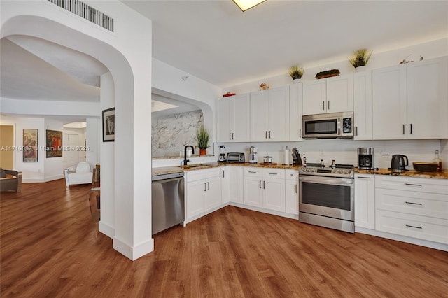 kitchen with stone counters, sink, appliances with stainless steel finishes, light hardwood / wood-style floors, and white cabinetry