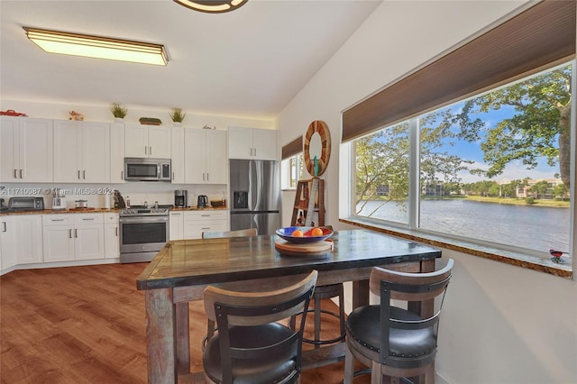 kitchen featuring a water view, white cabinetry, stainless steel appliances, and dark wood-type flooring