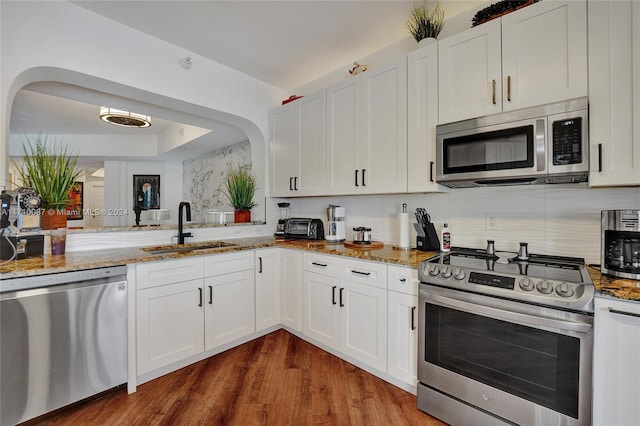 kitchen featuring dark wood-type flooring, sink, light stone counters, white cabinetry, and stainless steel appliances