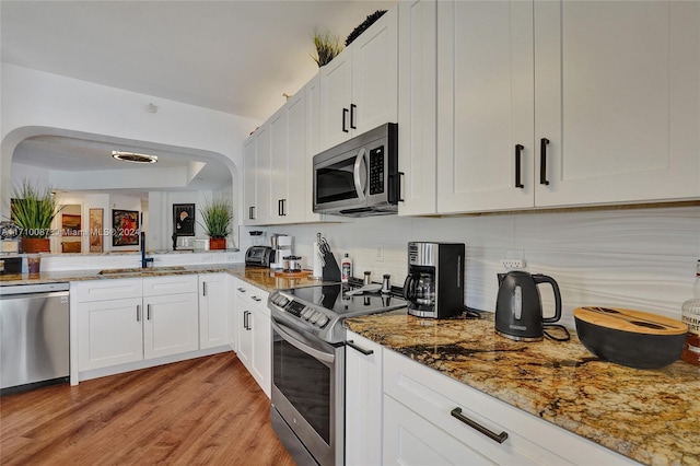 kitchen featuring white cabinetry, sink, stainless steel appliances, dark stone countertops, and light wood-type flooring