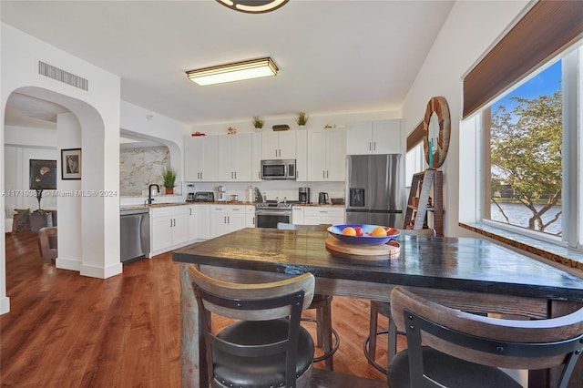 kitchen featuring stainless steel appliances, dark wood-type flooring, sink, dark stone countertops, and white cabinets