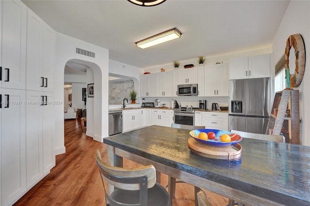 kitchen featuring hardwood / wood-style flooring, sink, white cabinetry, and stainless steel appliances