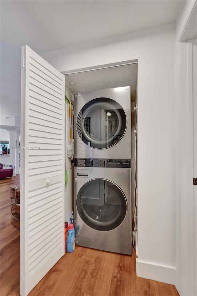 washroom featuring hardwood / wood-style floors and stacked washer and dryer