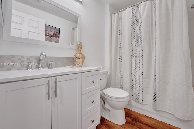 full bathroom featuring decorative backsplash, shower / tub combo, vanity, hardwood / wood-style flooring, and toilet