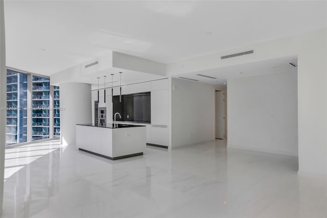 kitchen with white cabinetry, a center island, expansive windows, and sink