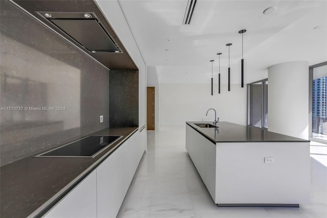 kitchen with black electric stovetop, sink, pendant lighting, white cabinets, and a kitchen island