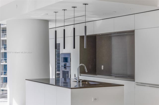 kitchen with white cabinetry, sink, stainless steel oven, decorative light fixtures, and black electric stovetop