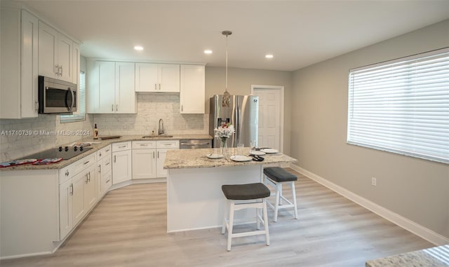 kitchen featuring light stone countertops, sink, a center island, white cabinets, and appliances with stainless steel finishes