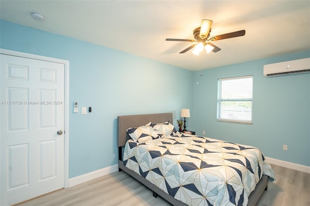 bedroom featuring ceiling fan, light hardwood / wood-style floors, and a wall mounted air conditioner