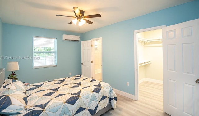 bedroom with a spacious closet, ceiling fan, a wall mounted AC, light hardwood / wood-style floors, and a closet