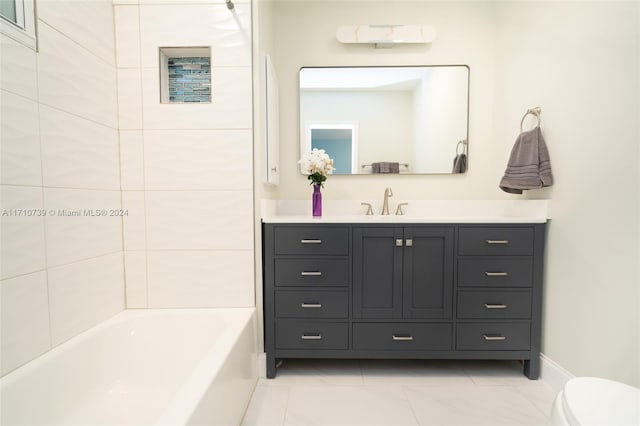 full bathroom featuring tiled shower / bath, vanity, and toilet