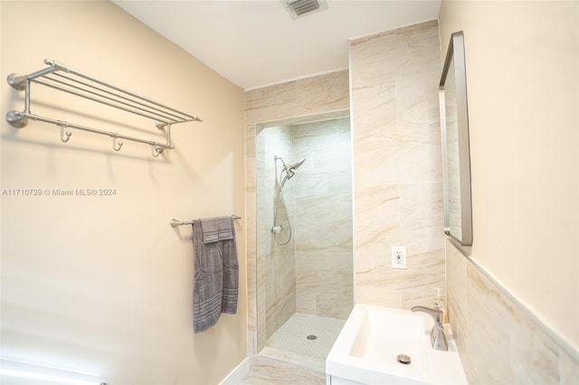 bathroom with a tile shower, tile walls, and sink