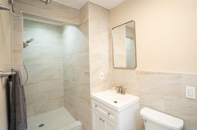 bathroom featuring a tile shower, vanity, toilet, and tile walls