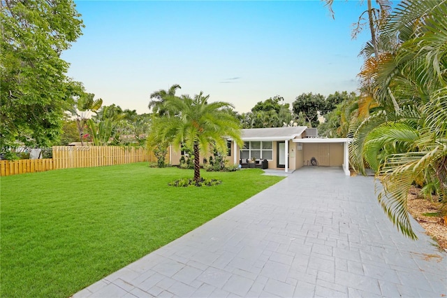 view of front of home with fence, a front lawn, and decorative driveway