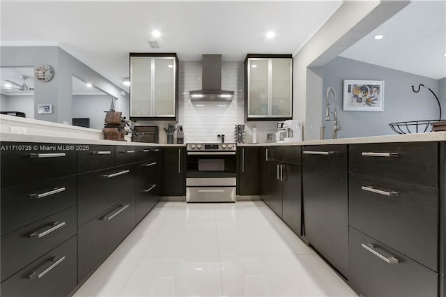 kitchen featuring light countertops, decorative backsplash, wall chimney exhaust hood, modern cabinets, and stainless steel range with electric stovetop