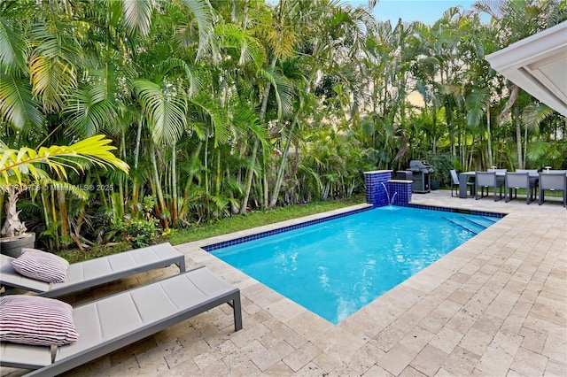 pool with outdoor dining space, a grill, and a patio