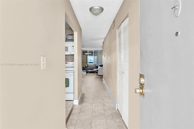 corridor with light tile patterned flooring and a textured ceiling