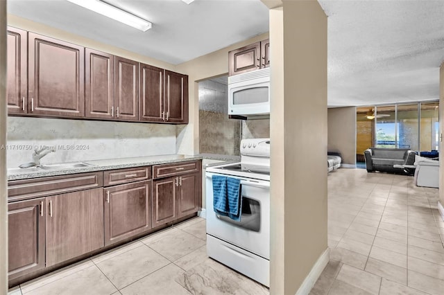 kitchen with light stone countertops, dark brown cabinets, a textured ceiling, white appliances, and sink