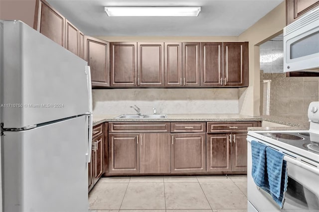 kitchen featuring decorative backsplash, sink, light tile patterned floors, and white appliances